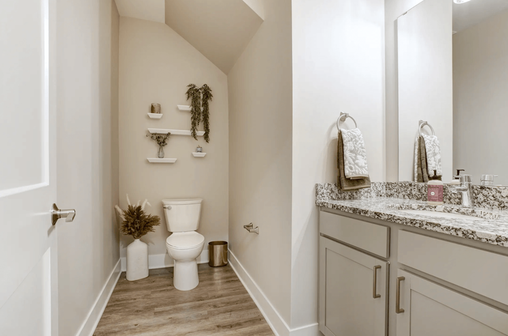 A white toilet sits in a bathroom next to a sink.