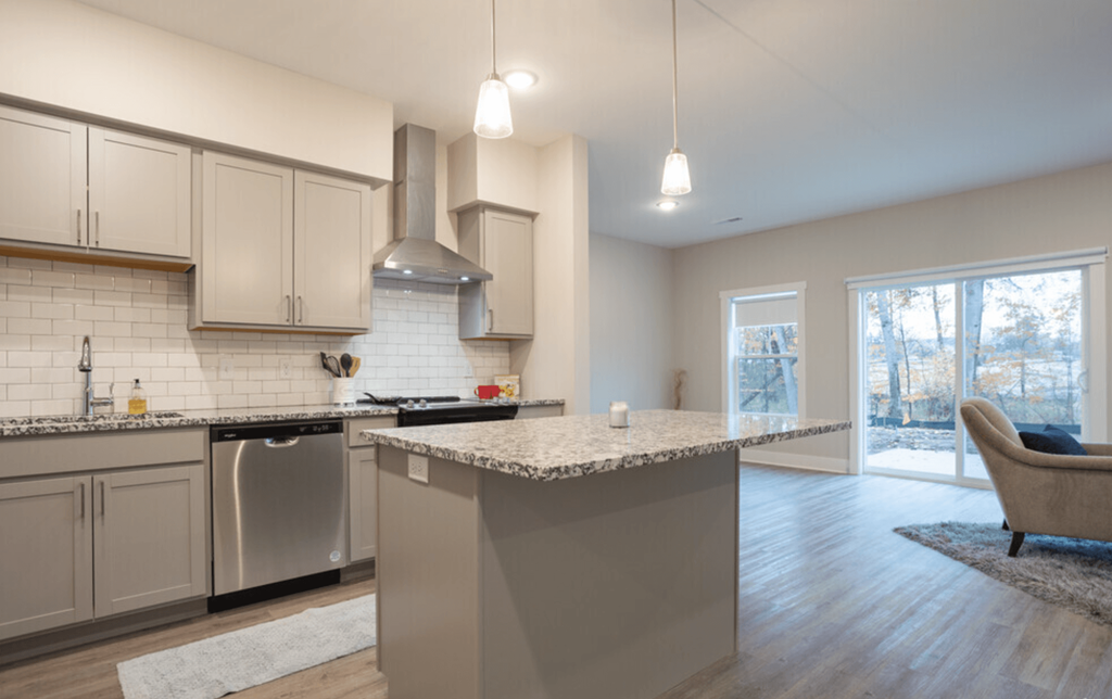 A modern kitchen with a large island and a stainless steel refrigerator.