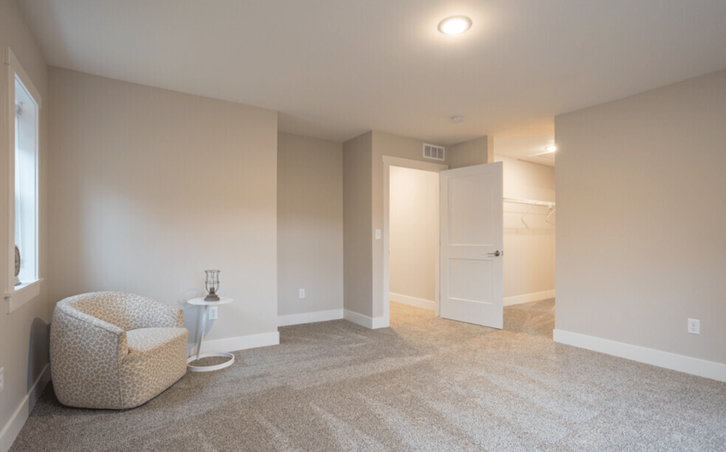 A spacious room with a chair and a small table.