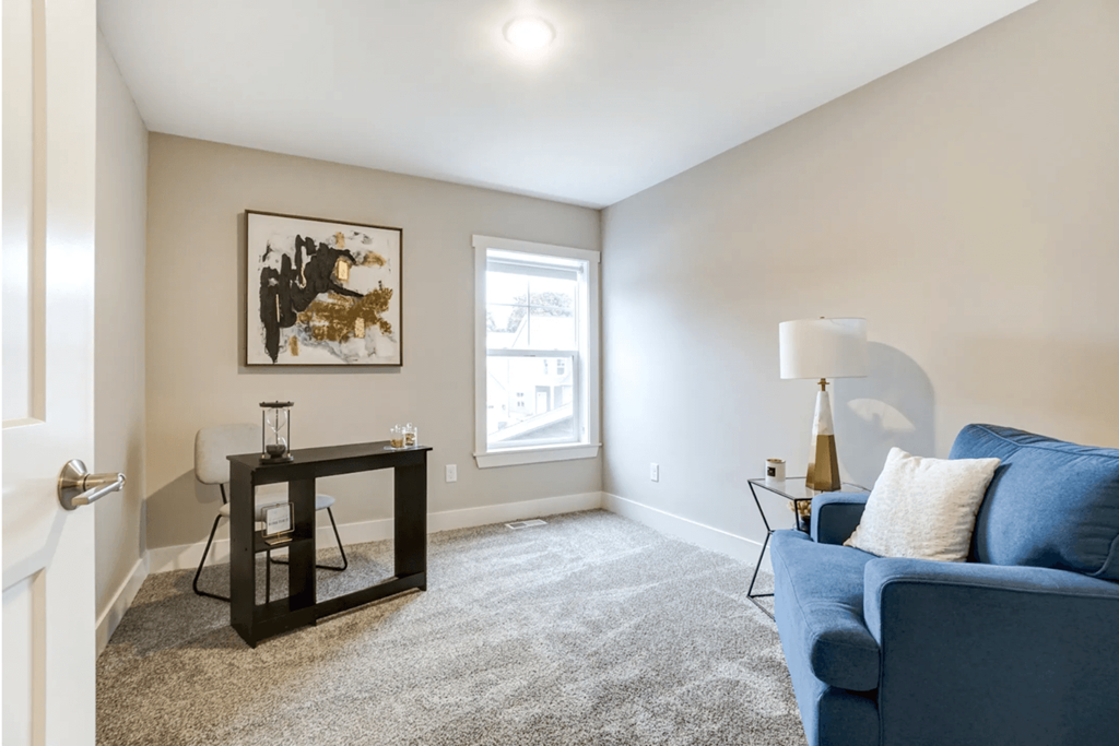 A living room with a blue couch and a painting on the wall.