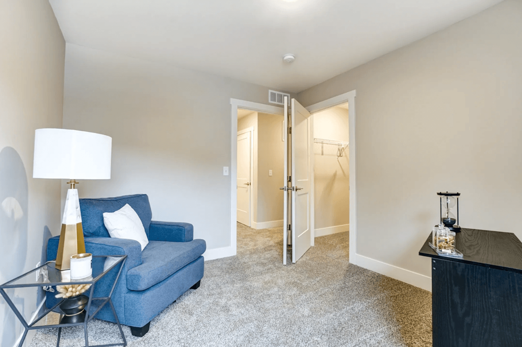 A blue sofa sits in a room with a lamp and a table.