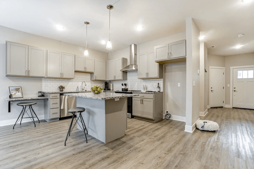 A kitchen with a white countertop and wooden flooring.