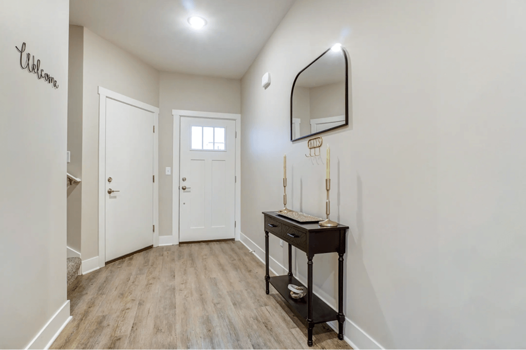 A hallway with a wooden floor and white walls.