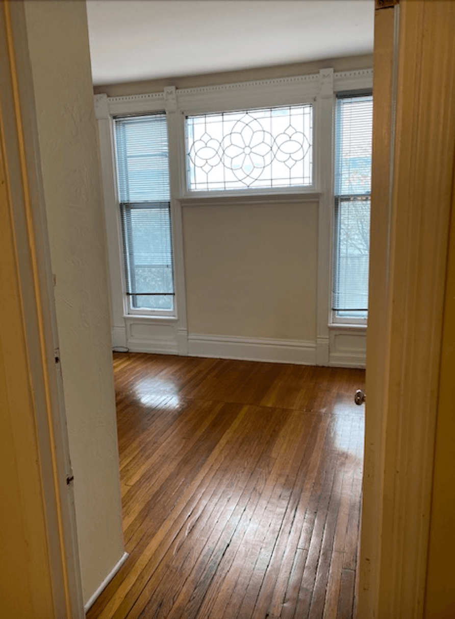 an empty room with wood floors and a window