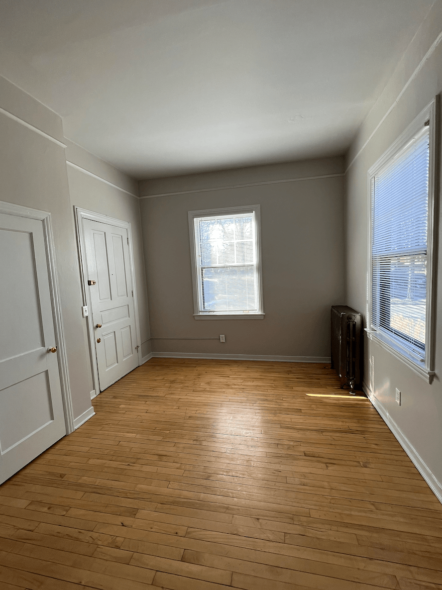 an empty living room with wood floors and a window