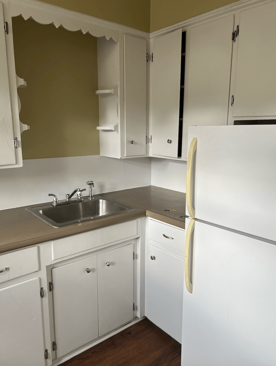 a kitchen with white cabinets and a sink and a refrigerator