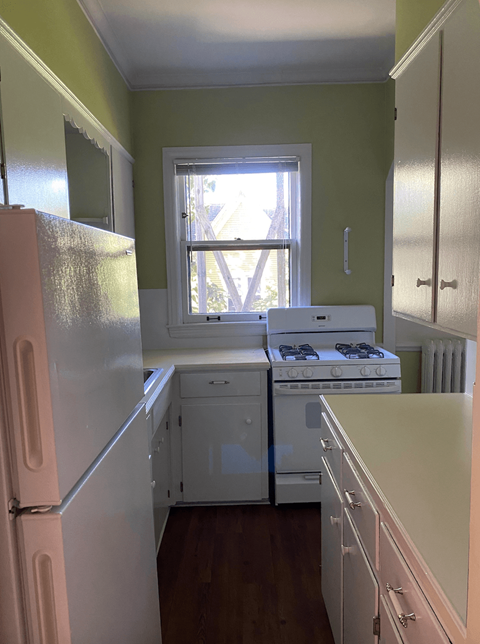 a kitchen with green walls and white appliances and a window