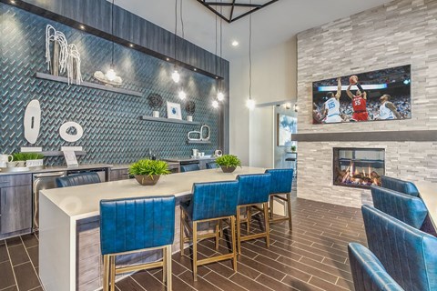 A modern kitchen with blue chairs and a fireplace.