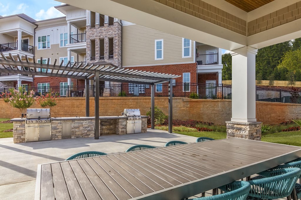 A patio with a grill and chairs is in front of a building at Crabtree Lakeside Apartments, Raleigh, 27612