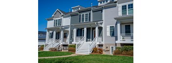 A row of houses with grey siding and white trim.