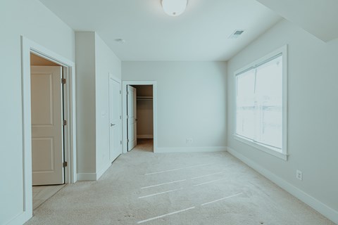 A spacious room with a carpeted floor and a large window.