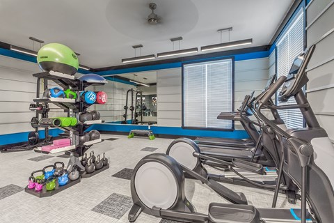 A gym with a row of treadmills and exercise equipment at Crabtree Lakeside Apartments, Raleigh