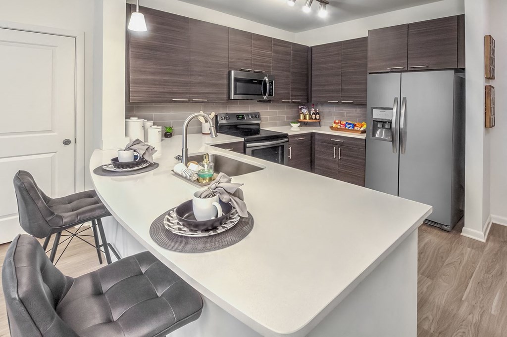 A modern kitchen with a white countertop and dark brown cabinets at Crabtree Lakeside Apartments, Raleigh, NC