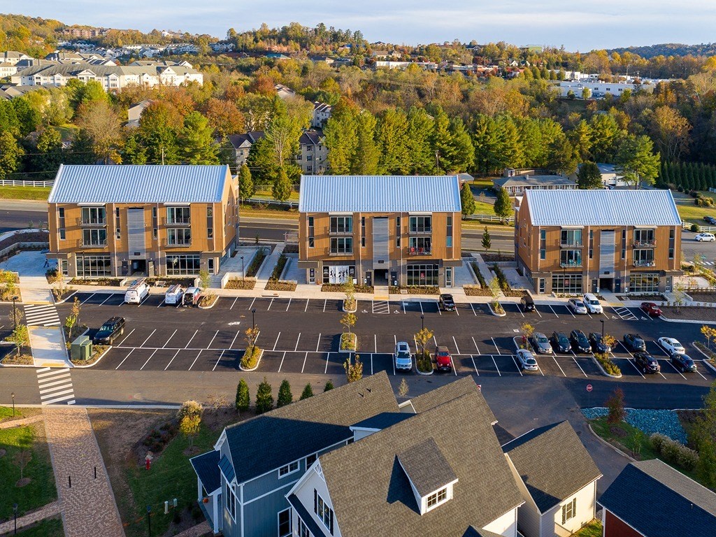 an aerial view of an apartment complex with parking lot and trees
