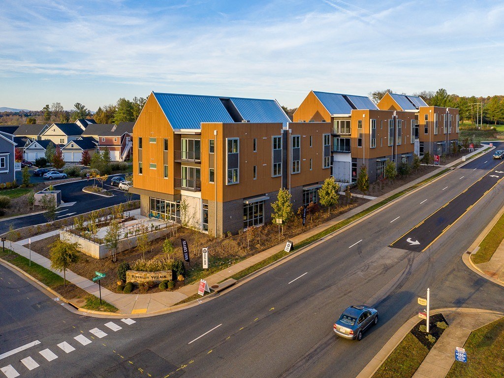 an aerial view of an apartment complex with a car driving down a street