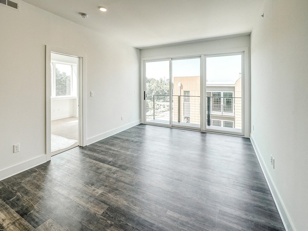 an empty living room with sliding glass doors and a balcony