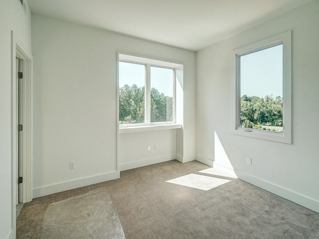 an empty living room with two windows and a door