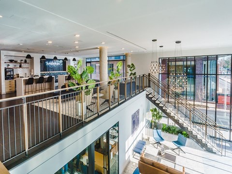 the lobby of a building with a staircase and tables and chairs