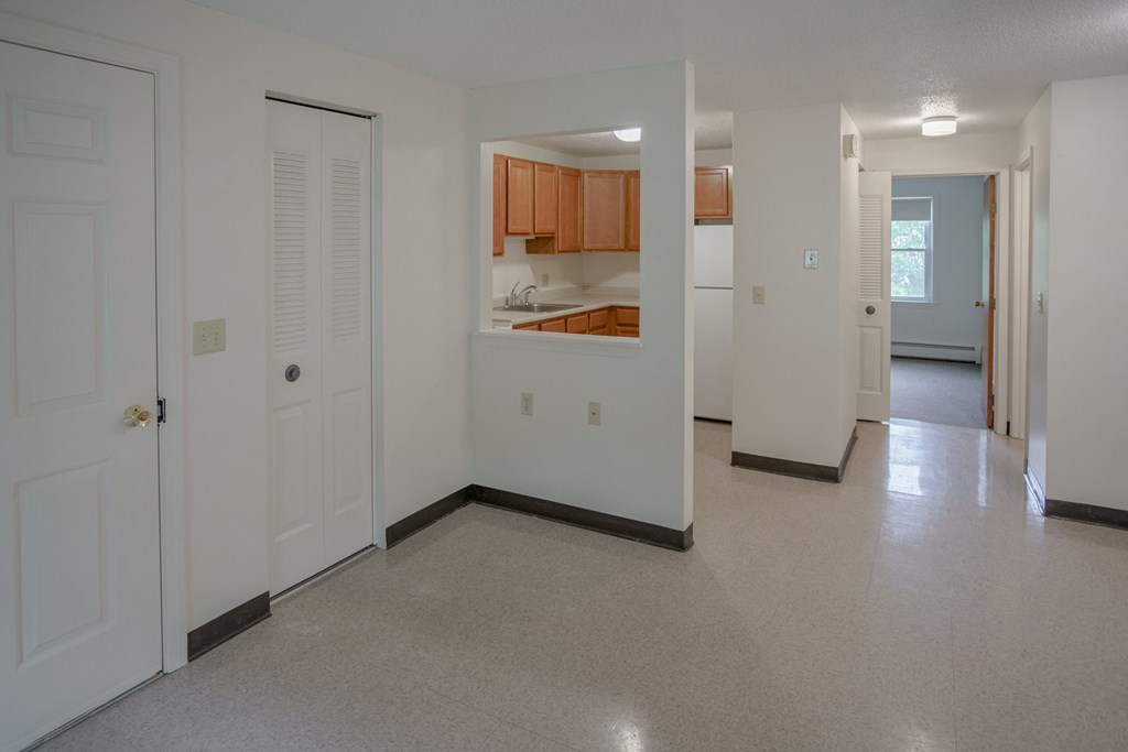 an empty living room and kitchen with white walls and tile floor