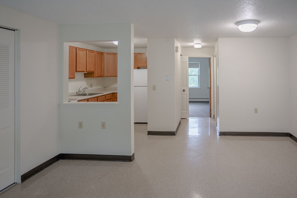 the view of a living room and kitchen from the entrance of an empty house
