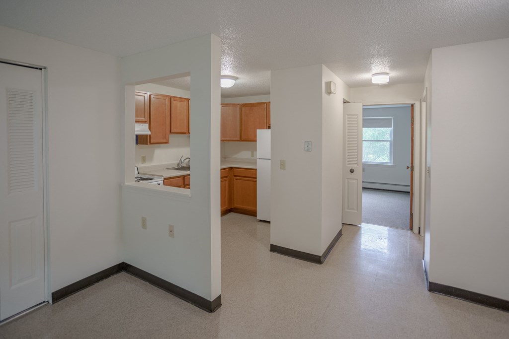 the view of a kitchen and living room from the entryway of an empty house