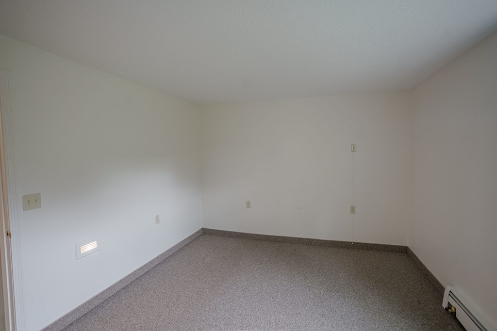an empty living room with white walls and carpet