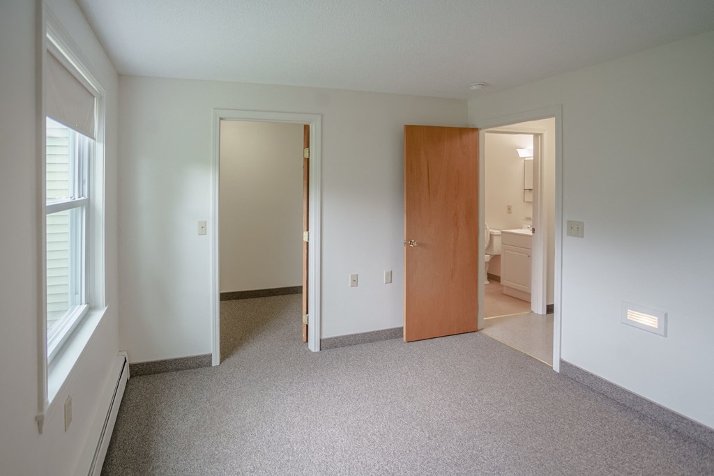 a bedroom with a carpeted floor and a door to a bathroom