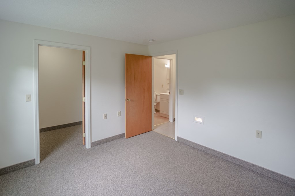 a bedroom with carpet and a door to a bathroom