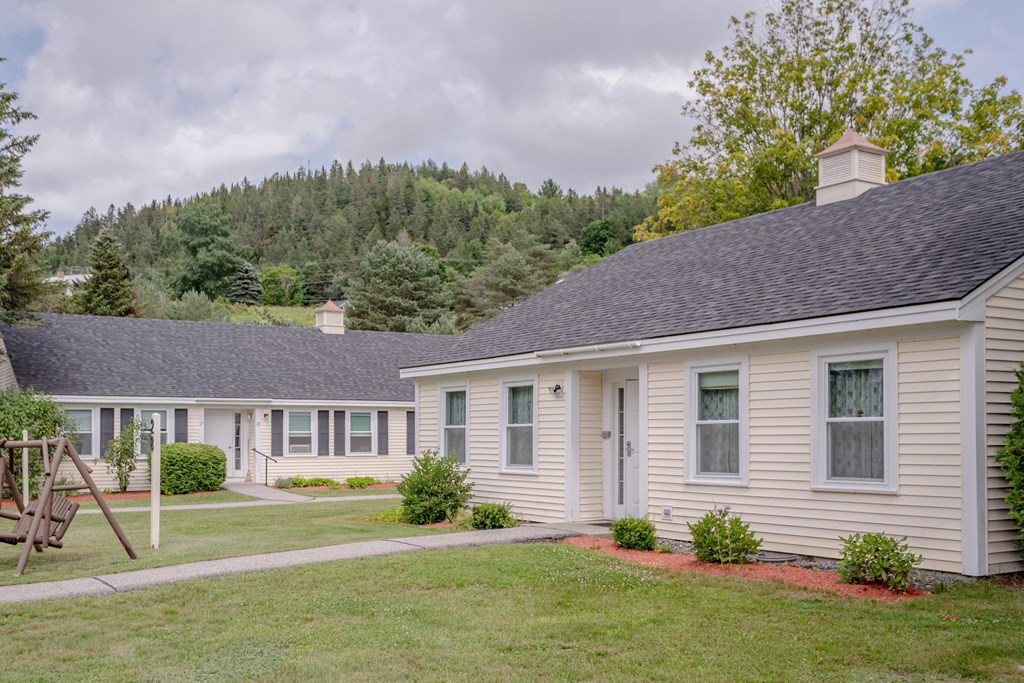 a group of white houses with grass and trees in the background
