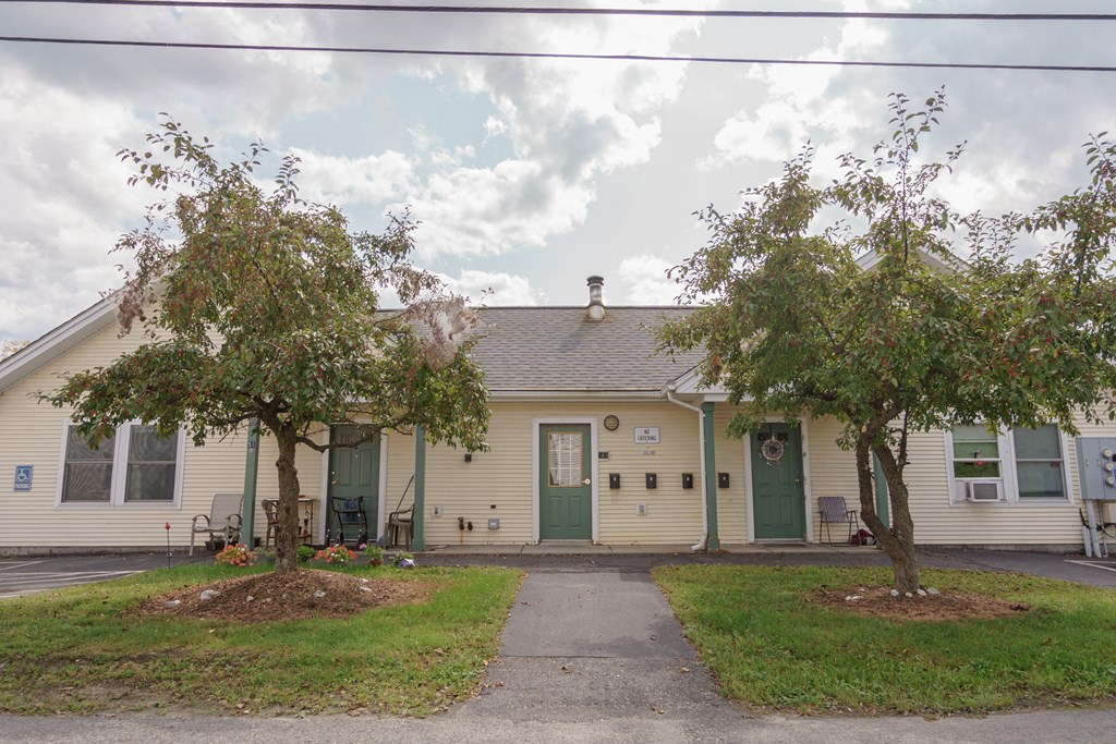 the front of a white house with two trees