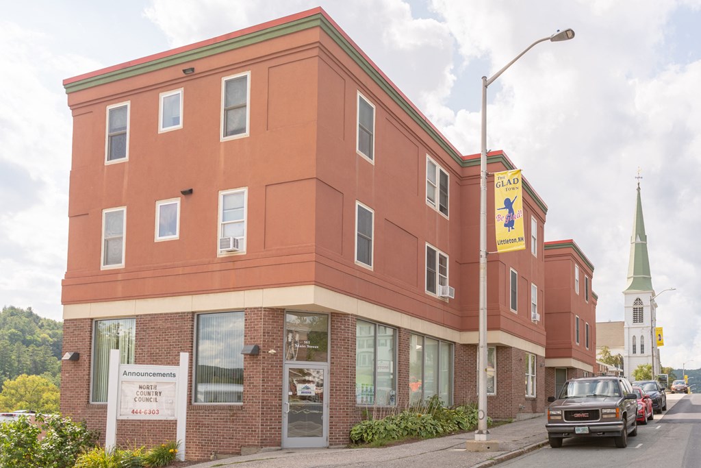 a large brick building with a church in the background