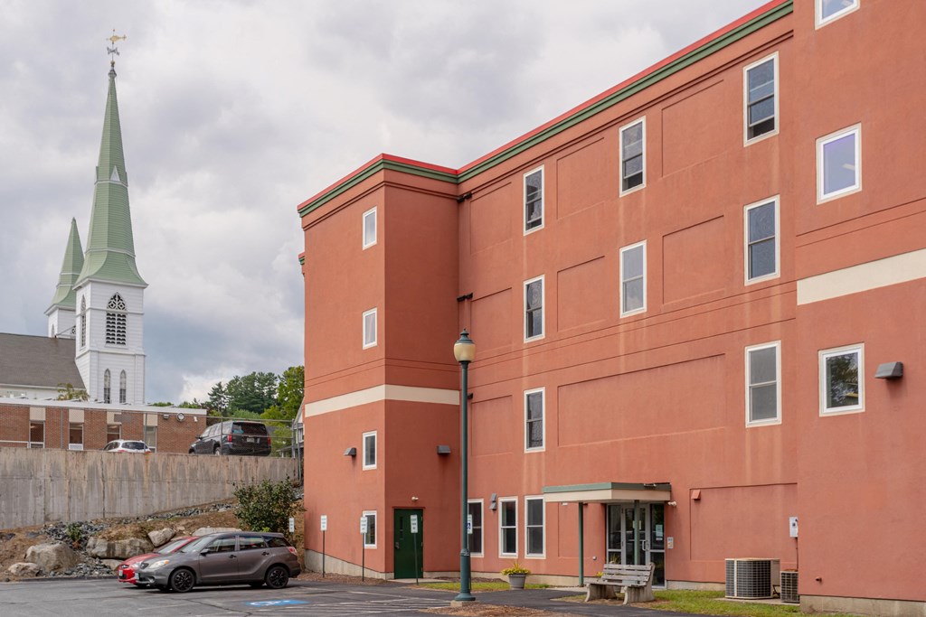 a large brick building with a church in the background