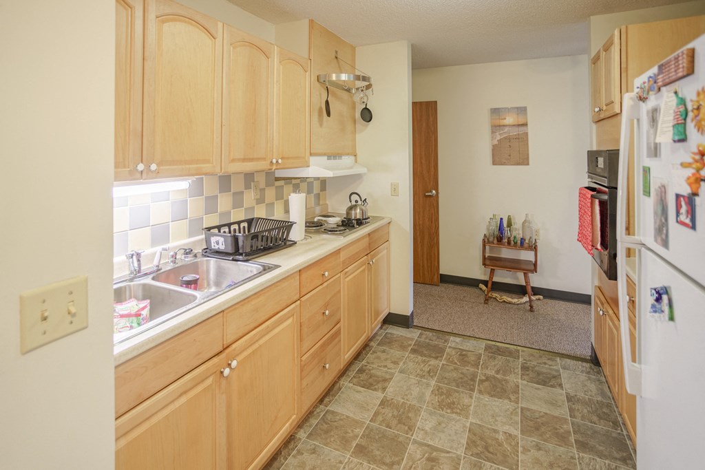 a kitchen with wooden cabinets and a sink and a refrigerator