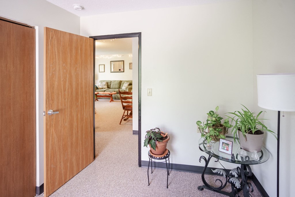 a living room with a door to a bedroom and a table with plants