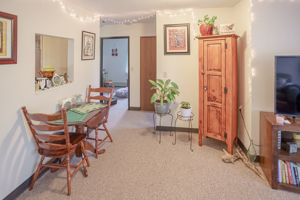 a living room with a dining room table and chairs and a television