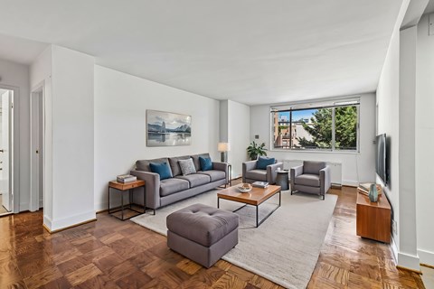 A living room with a grey couch and a painting on the wall.