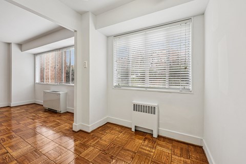 A room with a window covered by blinds and a radiator on the floor.