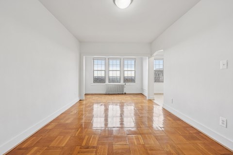 A room with wooden floors and a window with blinds.