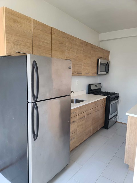 A kitchen with a stainless steel refrigerator and wooden cabinets.