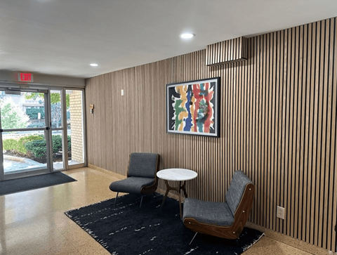 A room with a chair, a table, and a painting on the wall.