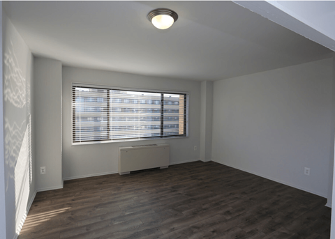 A room with wooden flooring and a window with blinds.