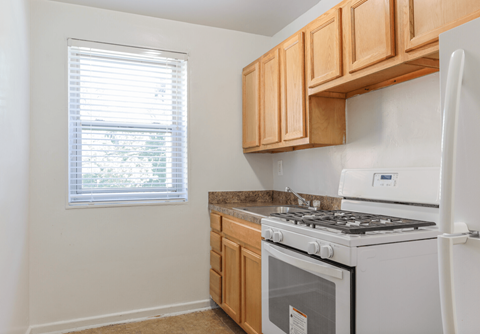 A kitchen with a white stove and wooden cabinets.