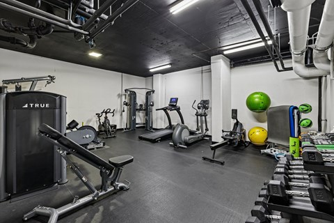 A gym with a variety of equipment including a leg press machine, a treadmill, and a stationary bike.