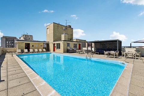 A large swimming pool in front of a building with a blue sky in the background.