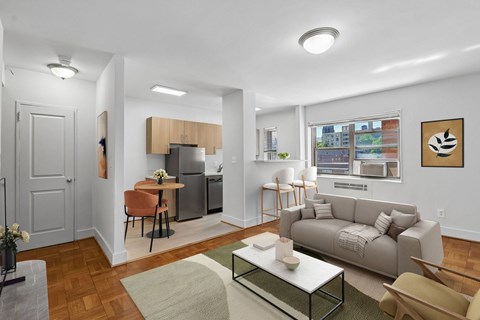 A modern living room with a grey couch, a coffee table, and a dining table with chairs.
