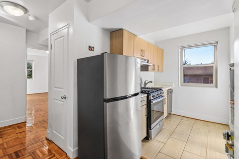 A kitchen with a stainless steel refrigerator and wooden cabinets.