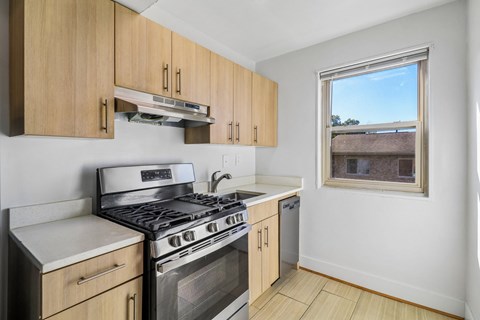 A kitchen with a stove top oven and wooden cabinets.