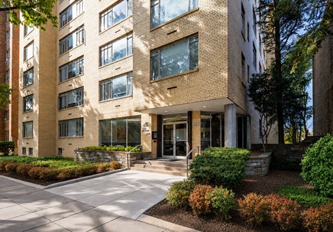 A modern building with a brick facade and a landscaped front yard.