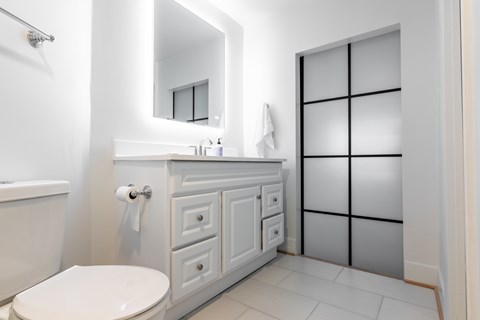 A white toilet sits next to a white cabinet with a mirror above it.