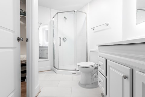 A white bathroom with a toilet, sink, and shower.